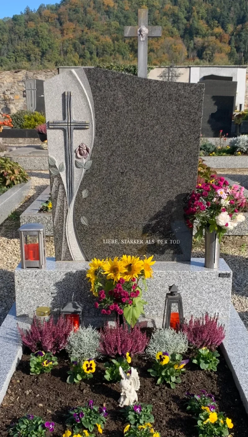 Individuell gestaltetes Einzelgrabmal aus Naturstein in Krems. Das Grabdenkmal mit persönlichem Ornament, einer Einfassung aus Tarn Granit und Grabschmuck aus Aluminium ist ein Meisterwerk des lokalen Steinmetz.