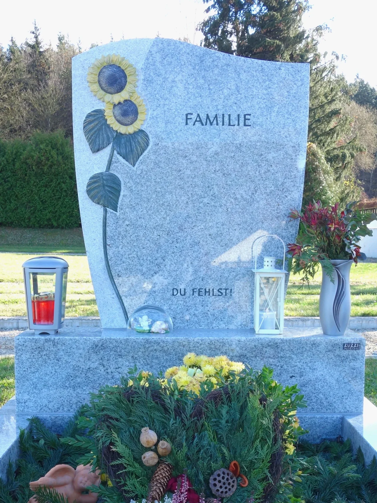 Moderne Grabanlage in Niederösterreich: Dieser Grabstein ist ein individuelles Grabdenkmal in minimalistischem Stil, mit einem Sonnenblumen-Ornament und passendem Grabzubehör.