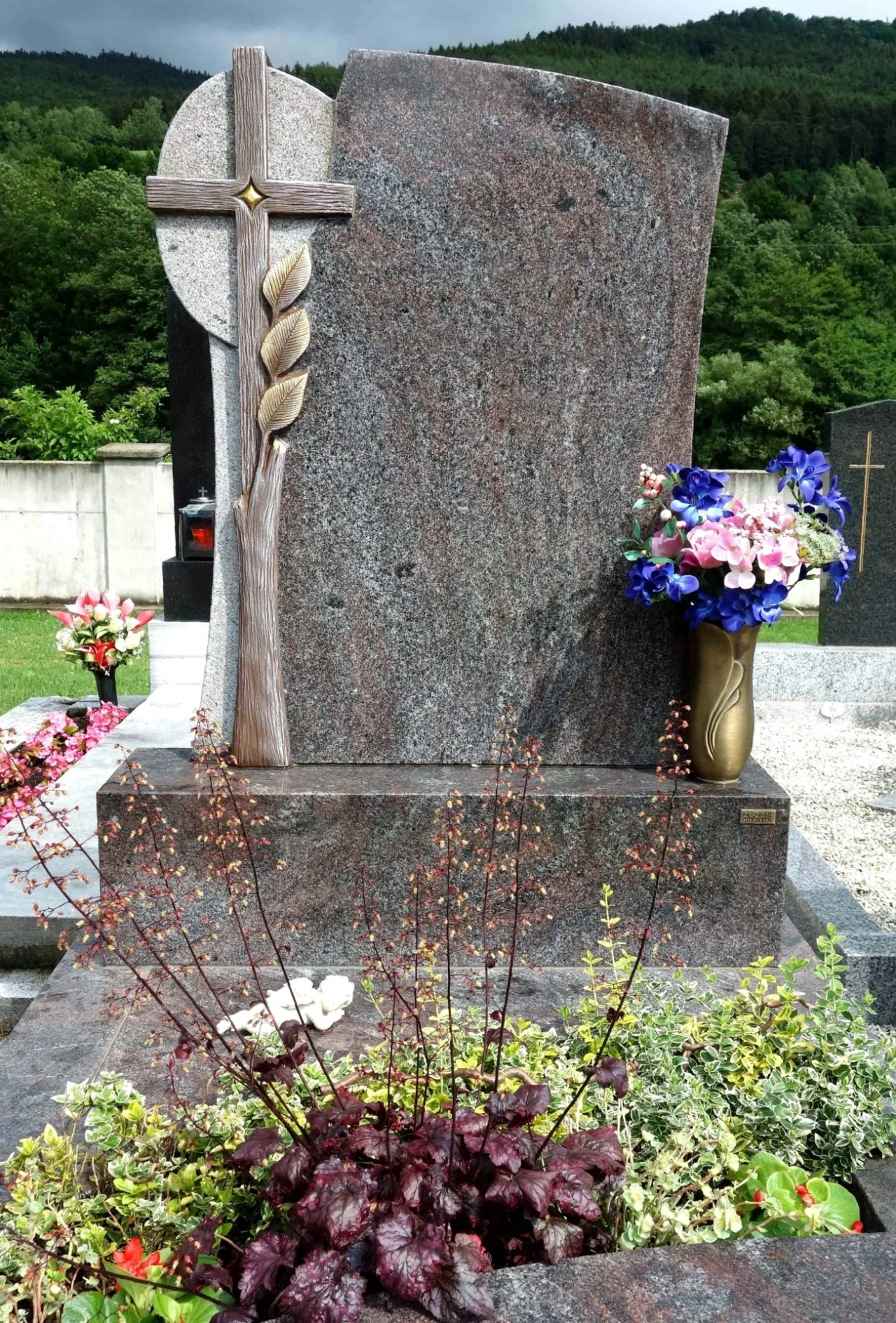 Individueller schlichter Grabstein mit Kreuz und Weizen-Ornamenten sowie passender Bronzelaterne und Vase.