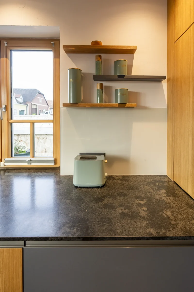 Küchenarbeitsplatte aus grauem Naturstein mit flächenbündigem Ceranfeld. Fachgerechte Steinmetz-Arbeit aus Niederösterreich.