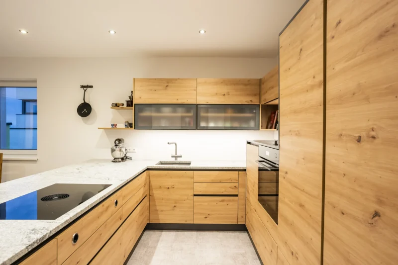 Gesamtansicht einer modernen Küche mit durchgehender Küchenarbeitsplatte aus poliertem Naturstein. Vom Steinmetz in Krems, Niederösterreich, gefertigt. Zeitlose Eleganz durch Granit.