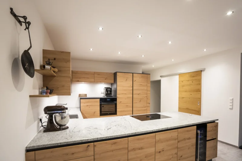 Kücheninsel mit Arbeitsplatte aus poliertem Granit. Professionell vom Steinmetz in Krems, Niederösterreich, gefertigt. Robuster Naturstein als Mittelpunkt der Küche.