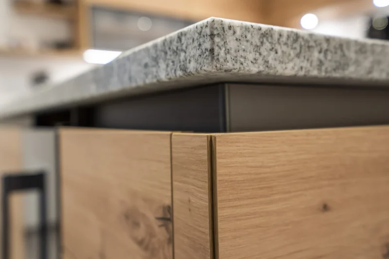Detailaufnahme der perfekt verarbeiteten Eckverbindung einer Küchenarbeitsplatte aus poliertem Granit. Präzise Steinmetz-Arbeit aus Krems, die höchste Qualität in jeder Fuge zeigt.