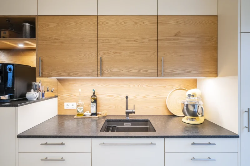 Nahaufnahme einer Spüle, perfekt eingelassen in eine Küchenarbeitsplatte aus poliertem Coffee Brown Granit. Präzise Steinmetz-Arbeit in Niederösterreich.