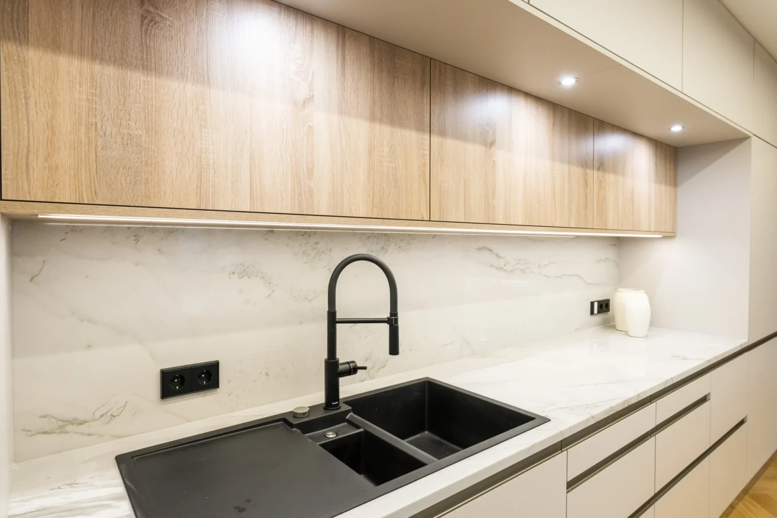 Partnerfirmen 3 Nahaufnahme einer Spüle, perfekt integriert in eine Küchenarbeitsplatte aus weißem poliertem Naturstein. Präzise Steinmetz-Arbeit aus der Region Krems.